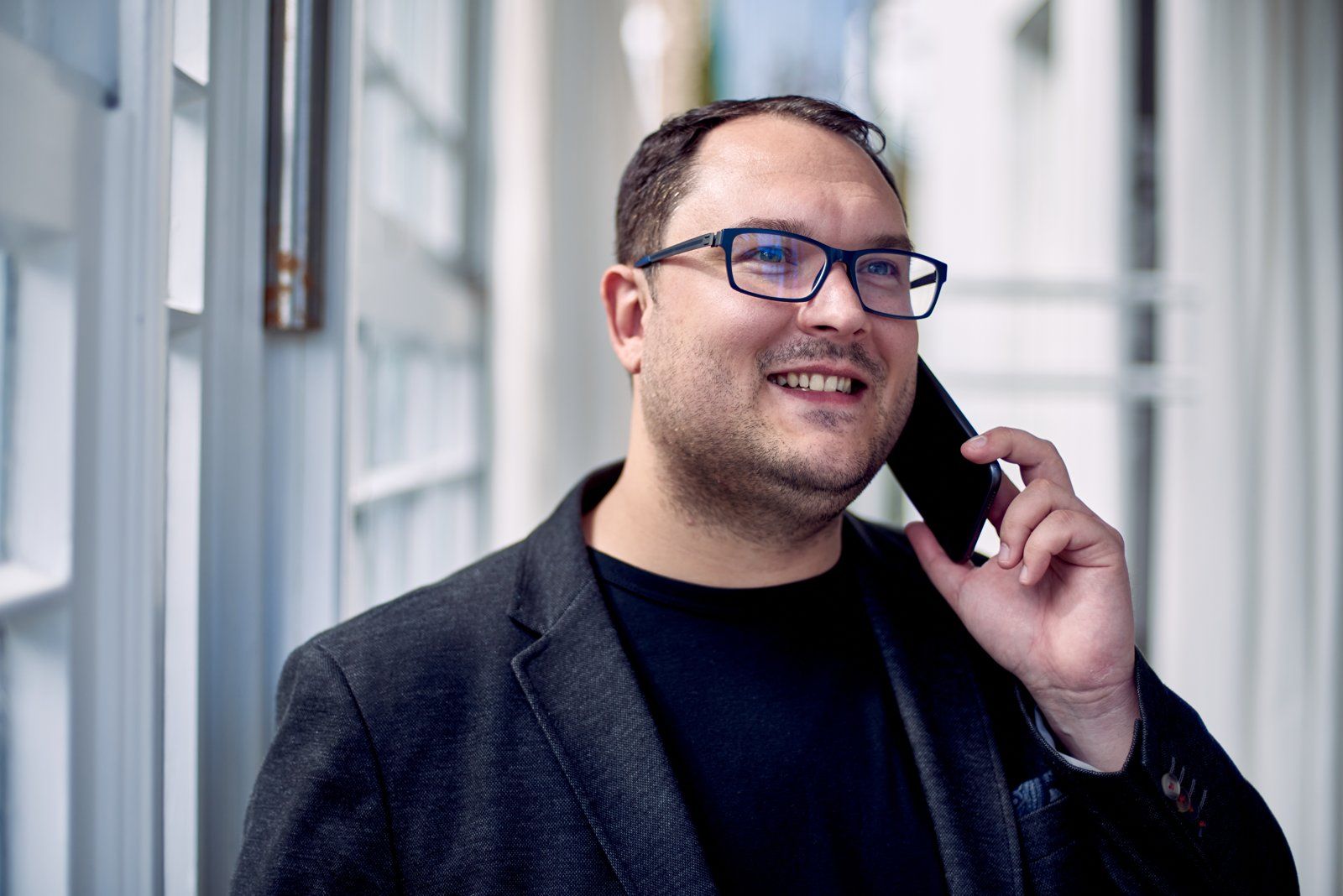 Thomas Schacht telefoniert lächelnd am Fenster